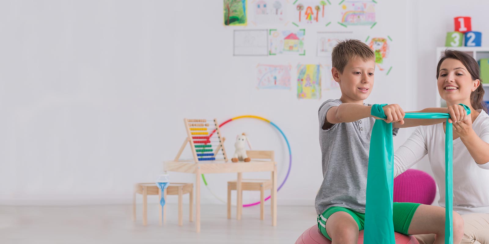 A boy and physical therapist doing arm stretches.
