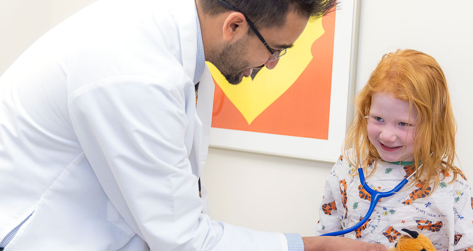 A young female patient laughs during a checkup with Omkar Phadke, MD