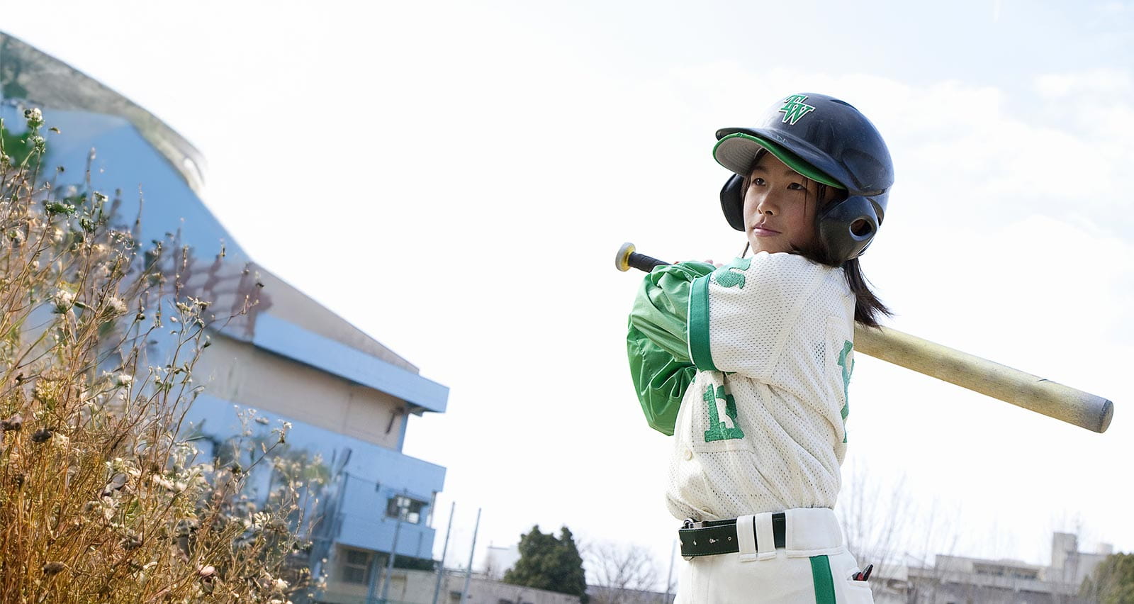 A young girl on a baseball team swings her bat