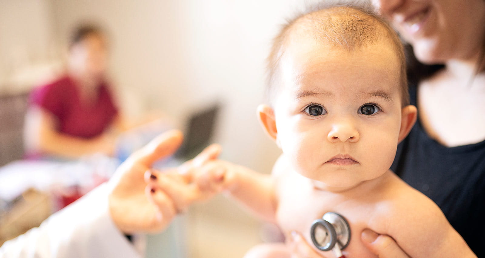 A surgeon places a stethoscope on an infant's chest