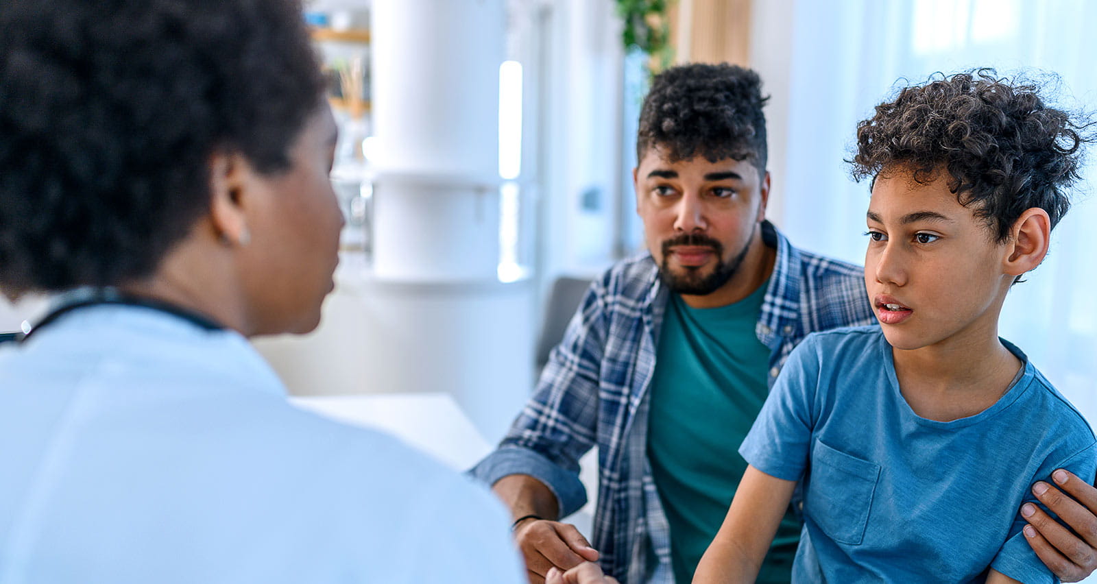 A concerned boy is being examined by a female pediatrician