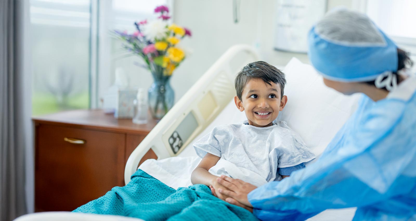 A female doctor checks in on a young male patient after his surgery.