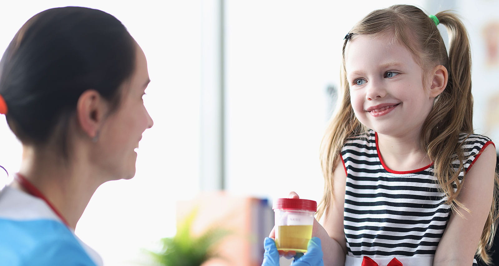 A little girl giving a urine sample to a nurse in a clinic