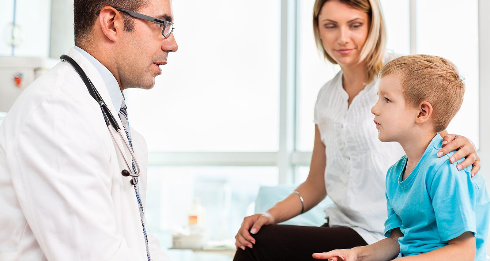 A doctor talking with a mother and child in his office