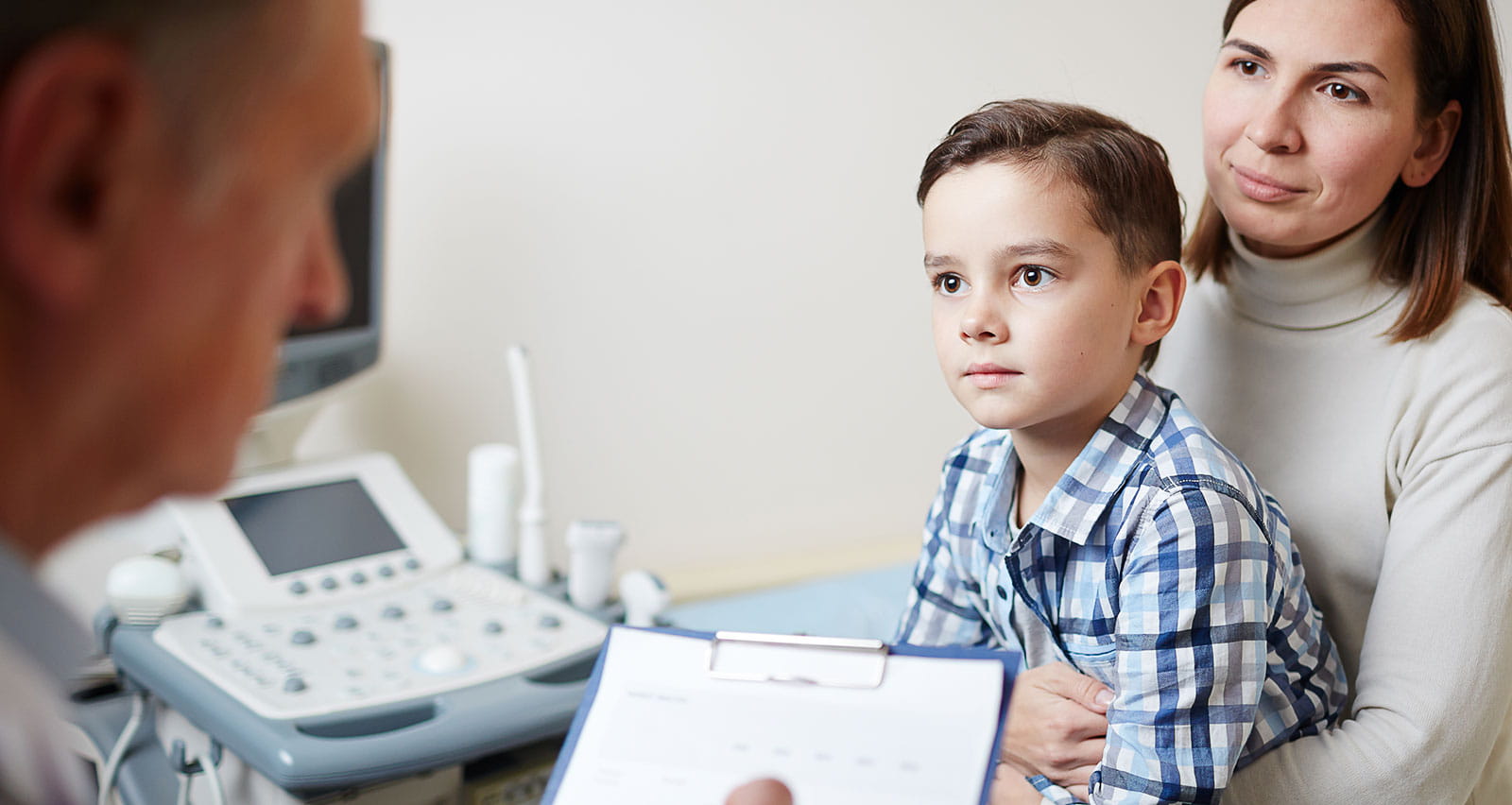 A young mother and her little son look at the doctor and listen to his advice during their appointment