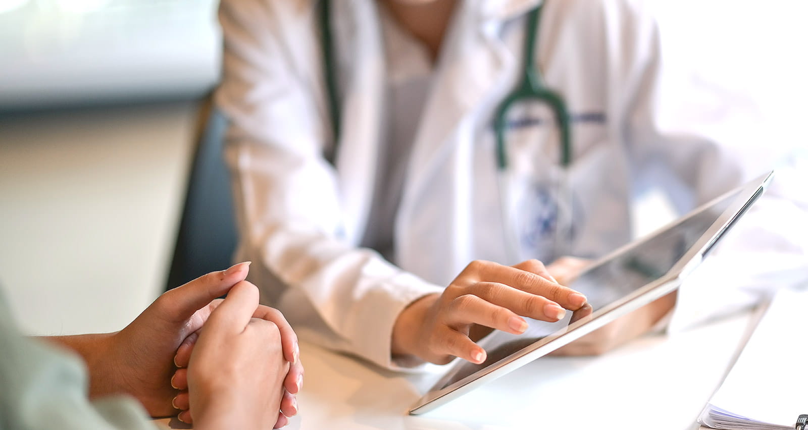 A doctor showing a patient medical information on a digital tablet