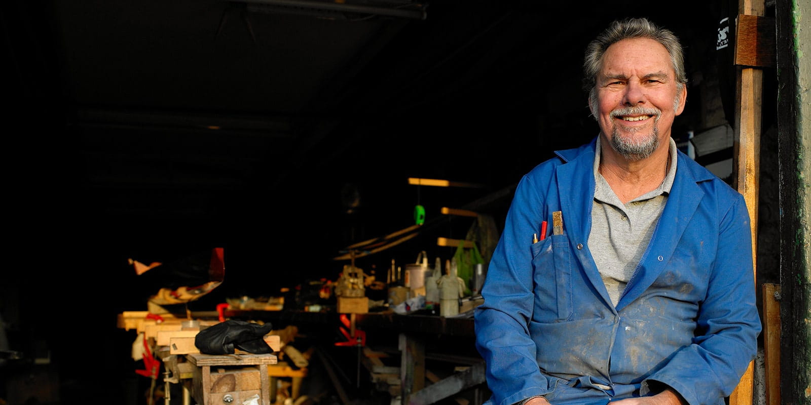 Male worker taking a break with coffee outside of workshop.