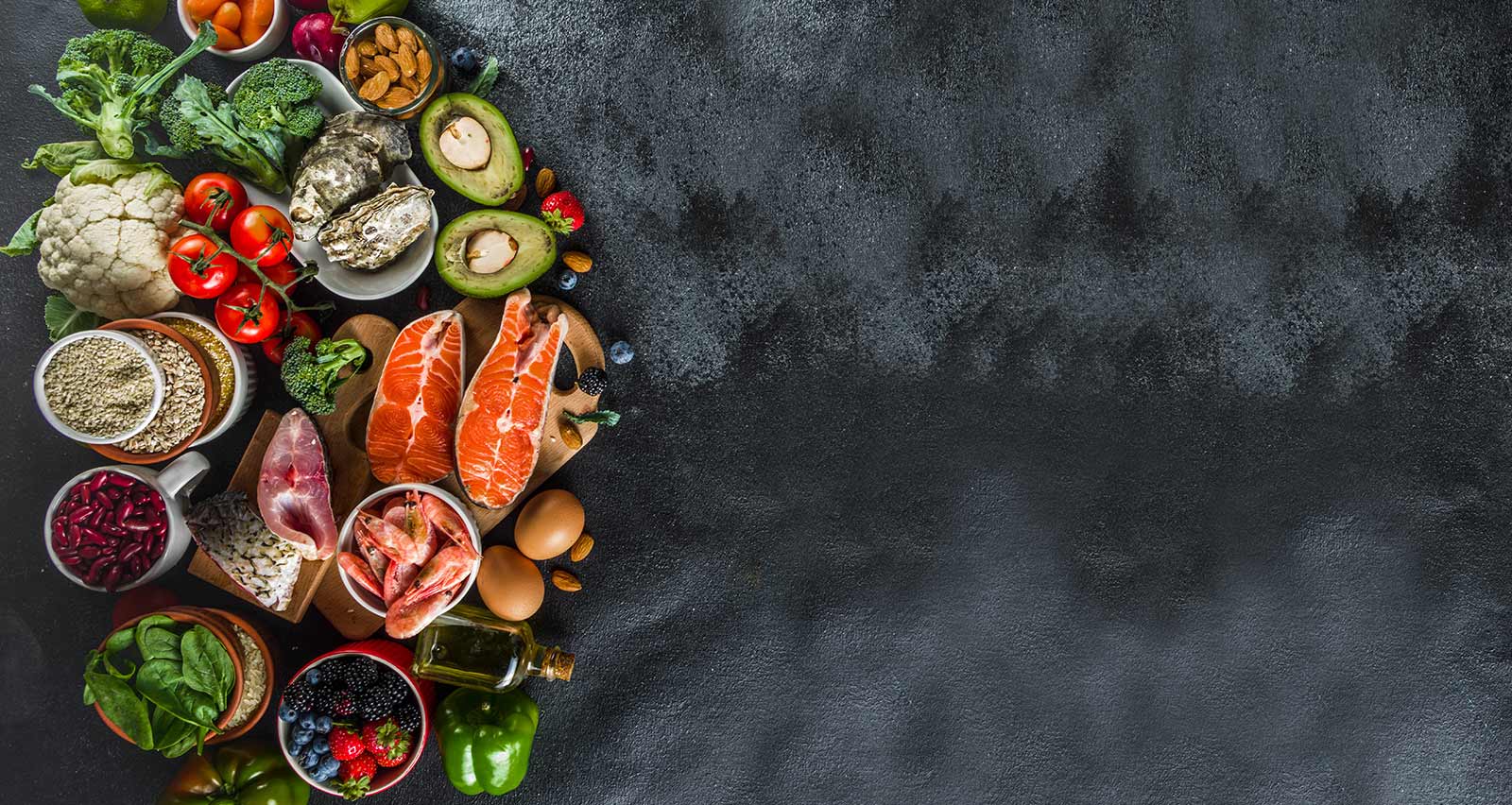 Pescatarian diet plan ingredients, healthy balanced grocery food, fresh fruit, berries, fish and shellfish clams, black stone concrete background copy space