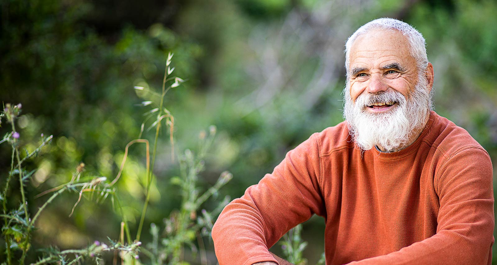 A bearded senior man rests outdoors