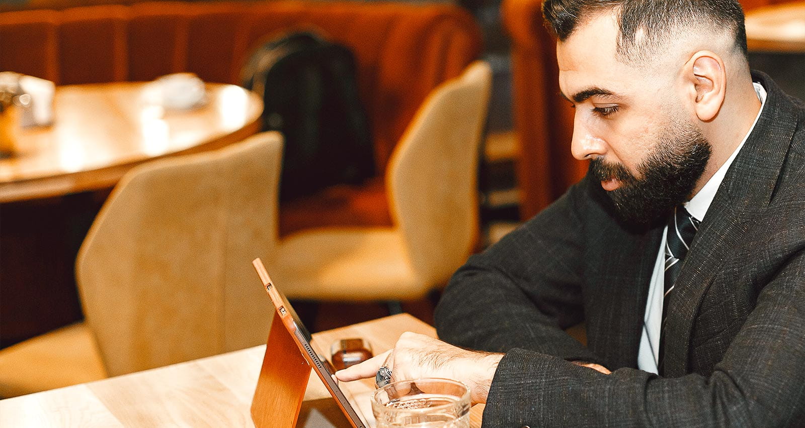 Man seated at a dining table reading from a digital tablet