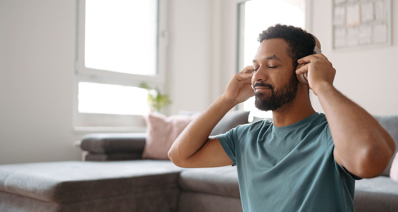 A man meditating alone at home while listening to mindfulness audio through wireless headphones
