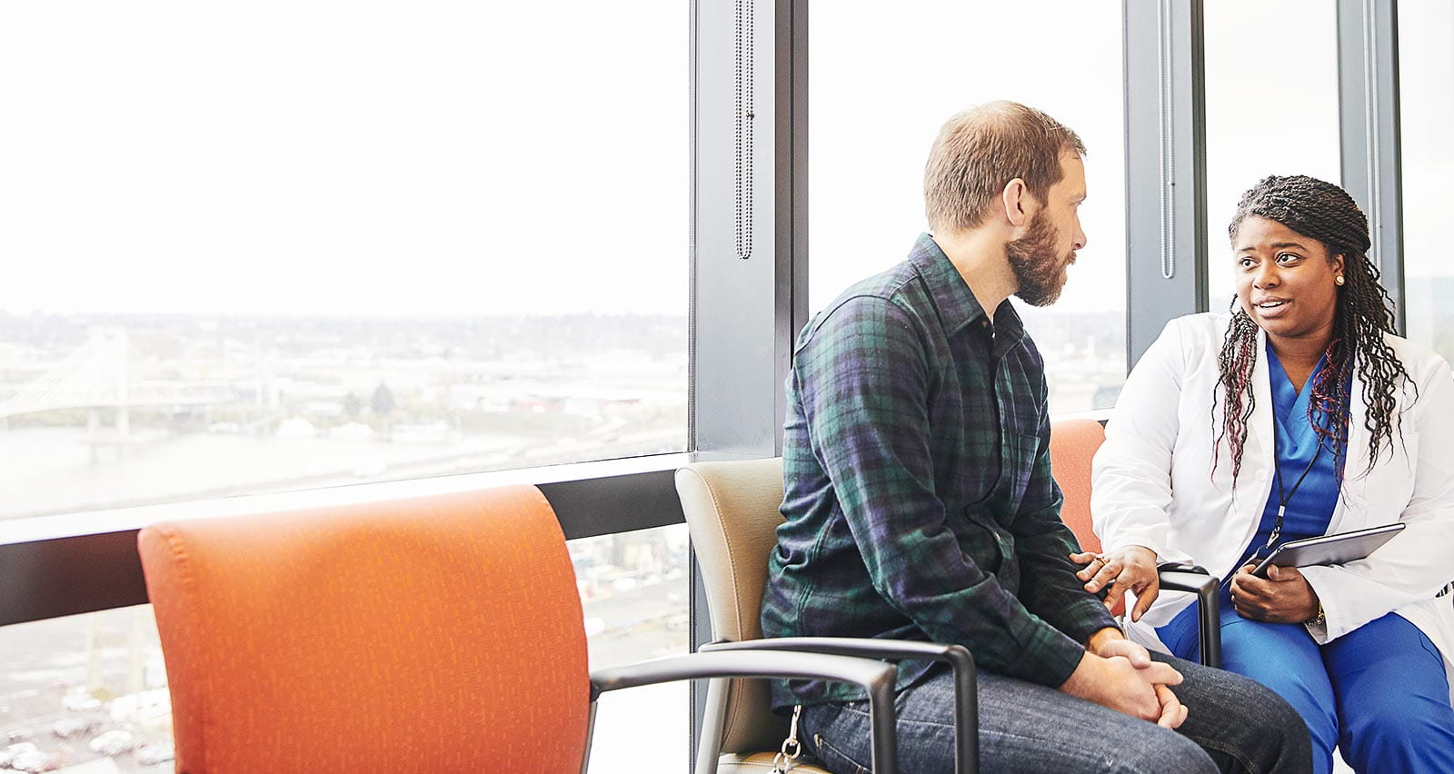 A female doctor speaks with a male patient in a hospital corridor