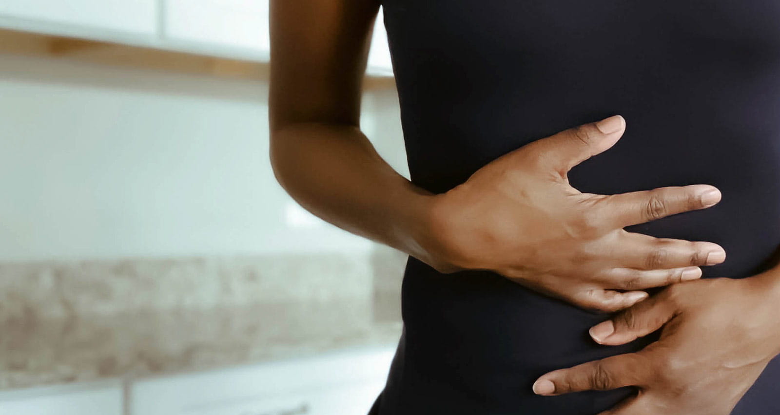 A woman clutches her stomach in pain