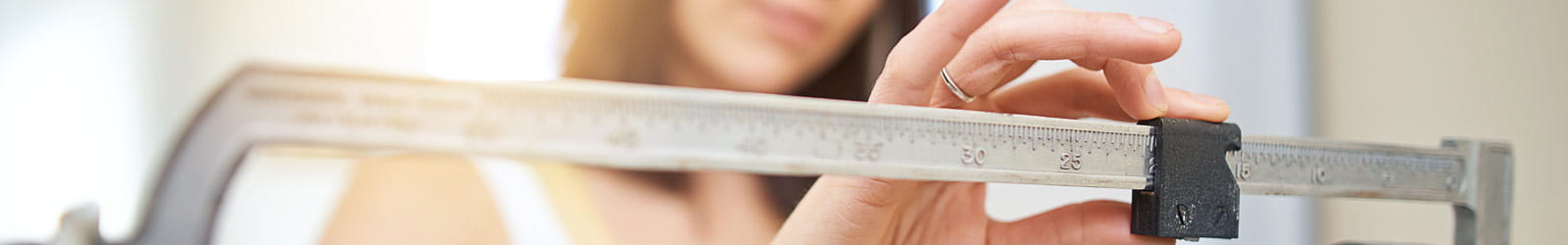 A young woman weighing herself on a scale