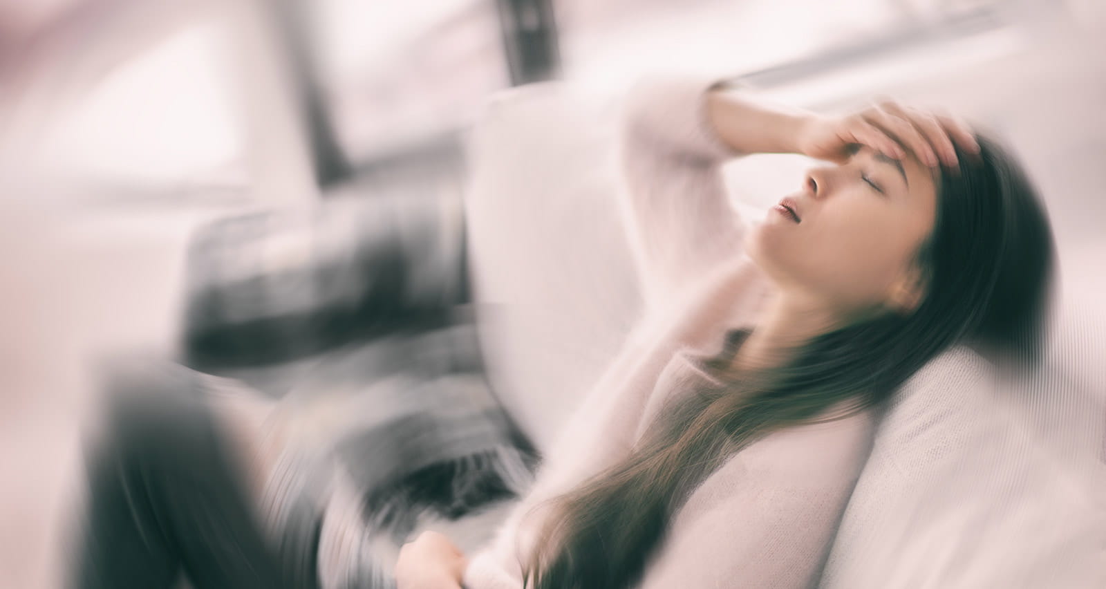 Woman suffering from dizziness from a balance disorder holds onto couch