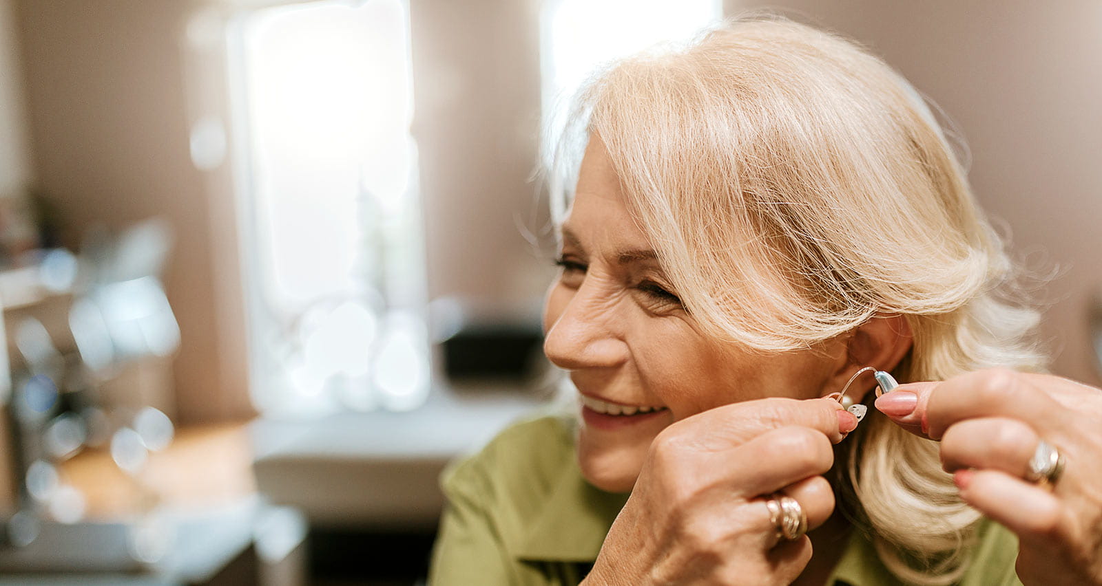 Smiling older woman inserting hearing aid