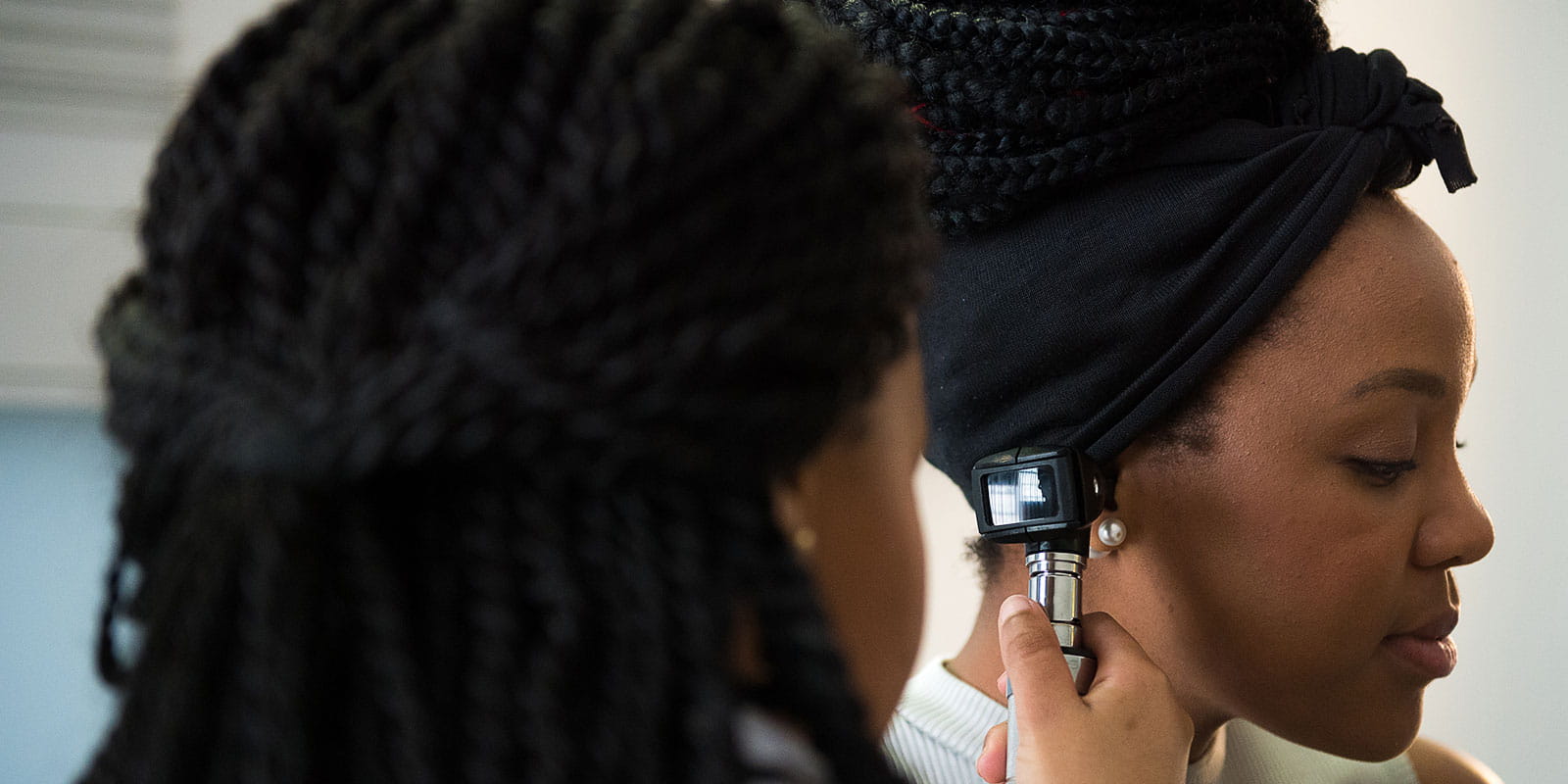 Female doctor examining woman's ear with otoscope