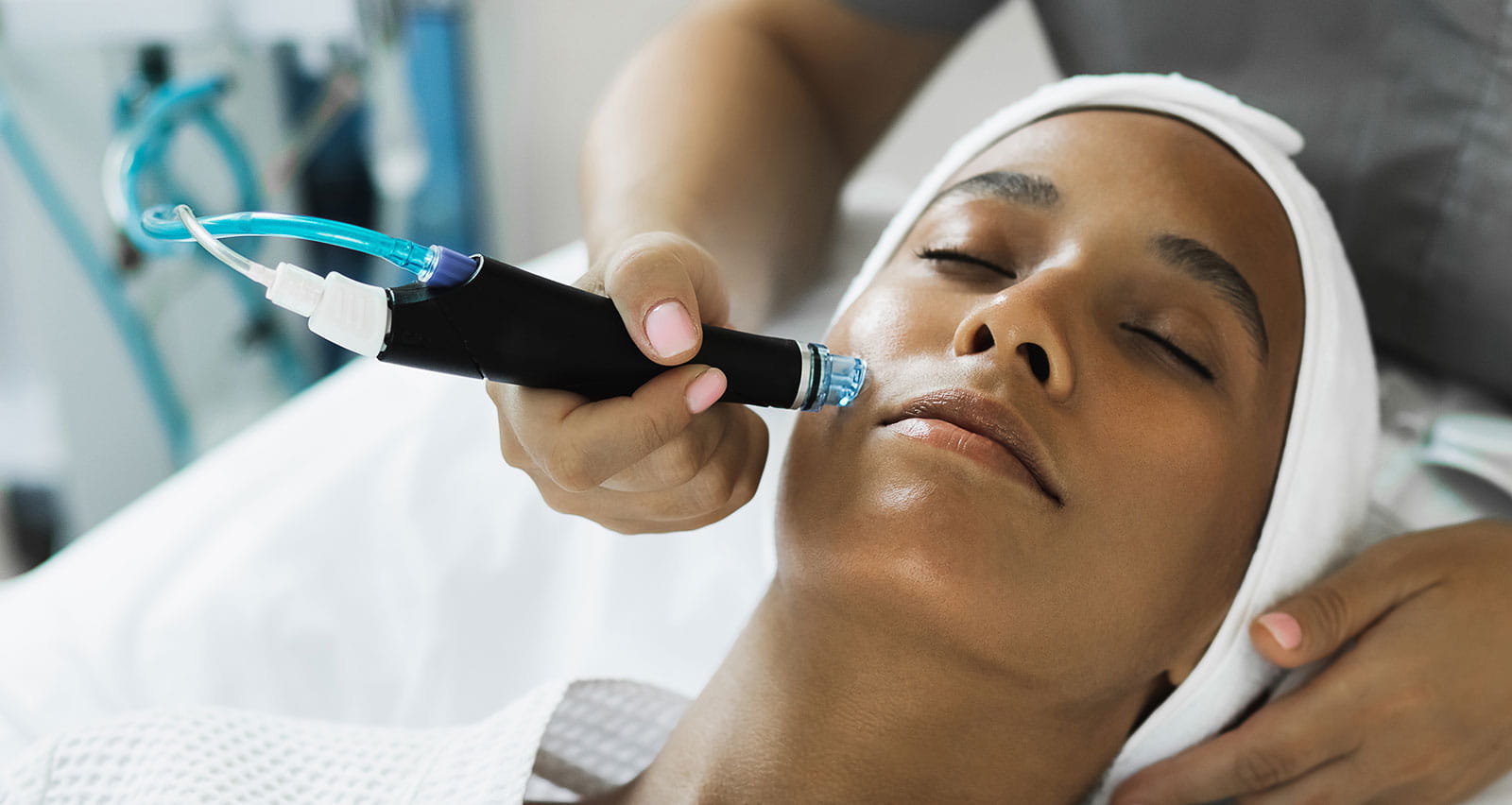 A young woman sitting in the cosmetologist's office receiving fractional mesotherapy treatment