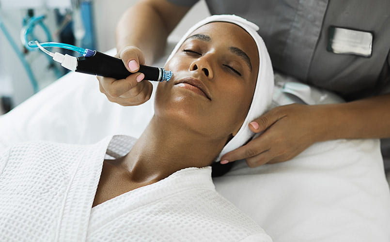 A young woman sitting in the cosmetologist's office receiving fractional mesotherapy treatment