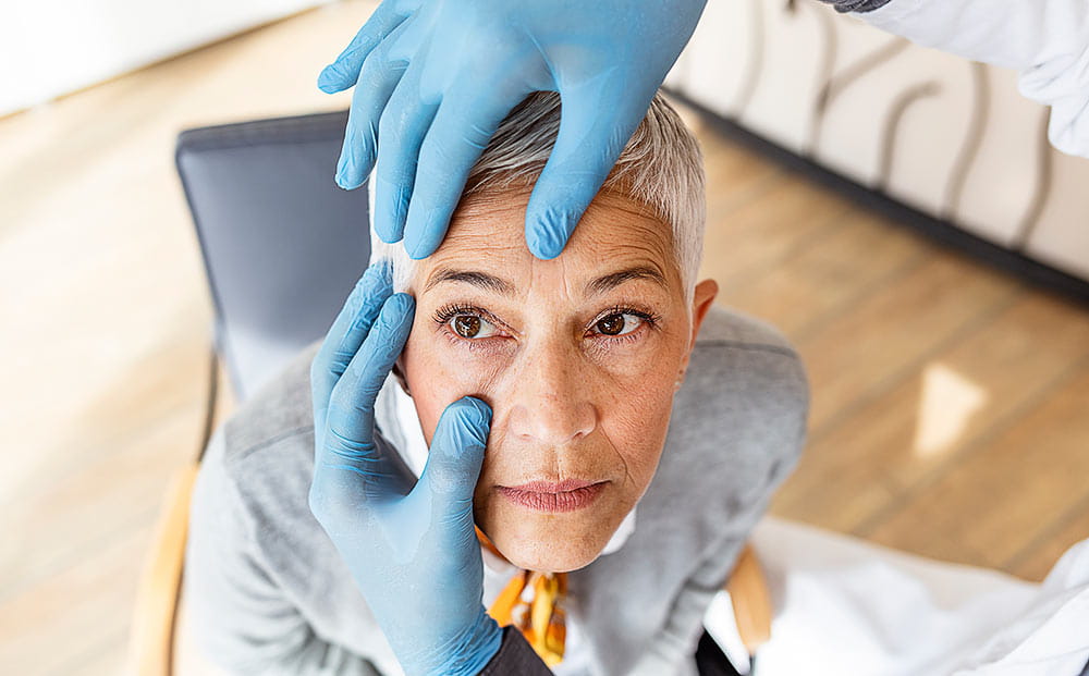 A doctor examining a senior woman’s eyes in his office