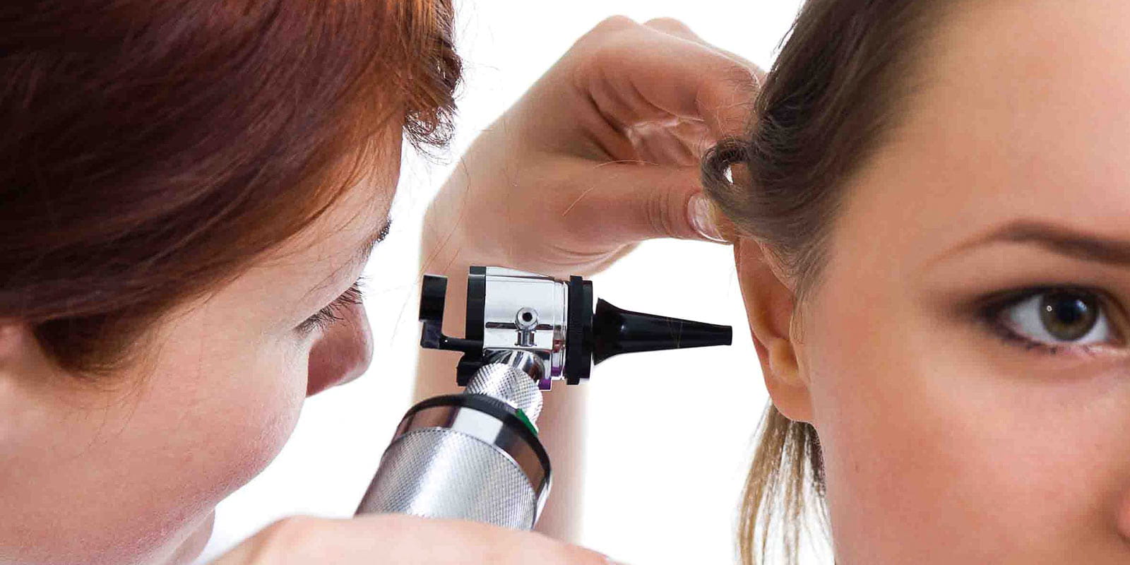 Physician performing otolaryngologycal exam on woman