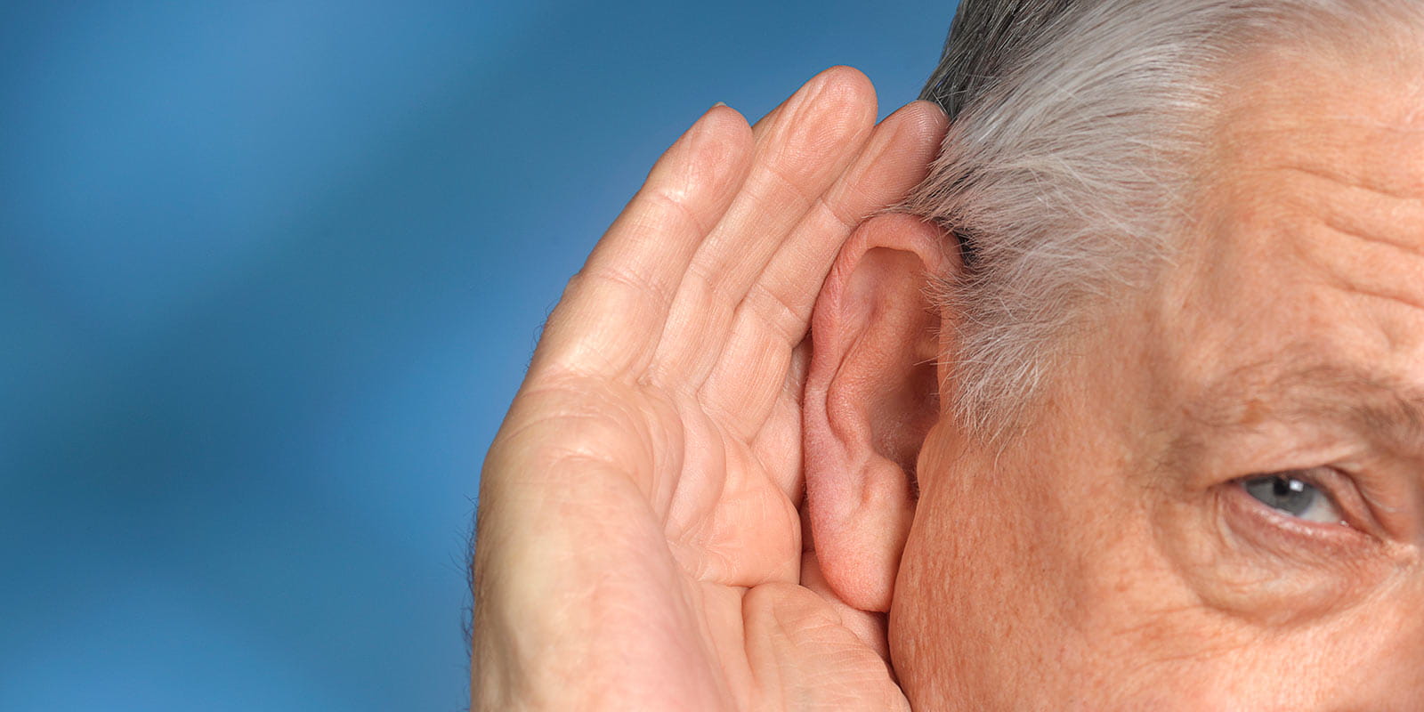 Man with hearing difficulties cupping his hand to his ear