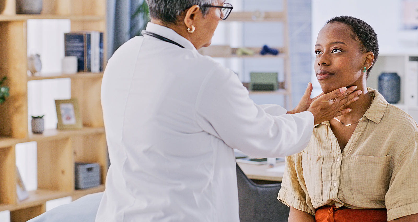 A provider performs a thyroid check on her female patient