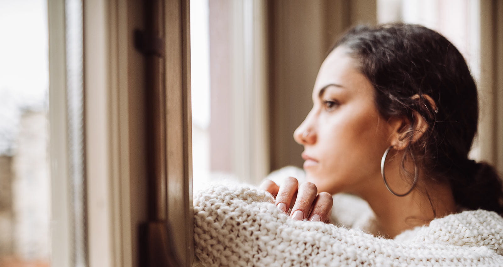 A pensive woman looks out of a window