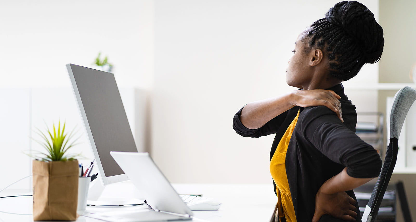 A woman in an office suffering discomfort from bad posture
