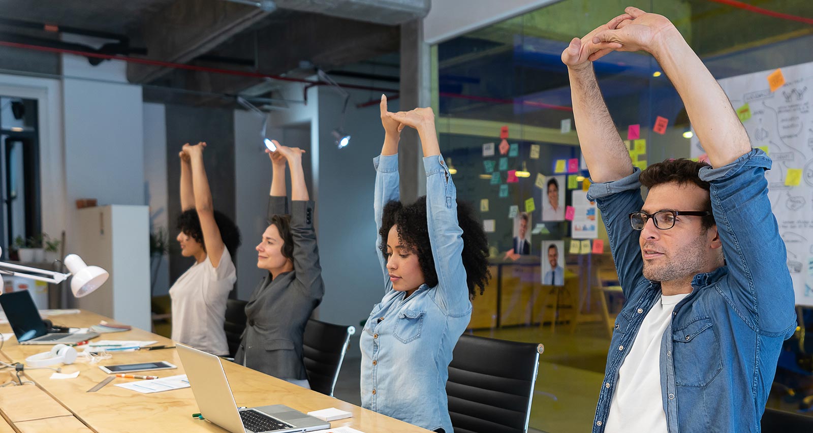 A group of employees doing stretching exercises during a business meeting at the office 