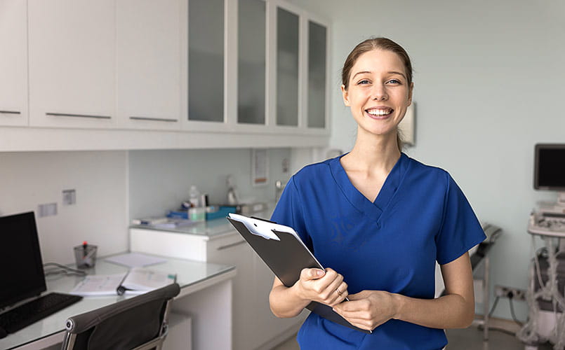 A smiling female nurse in blue scrubs
