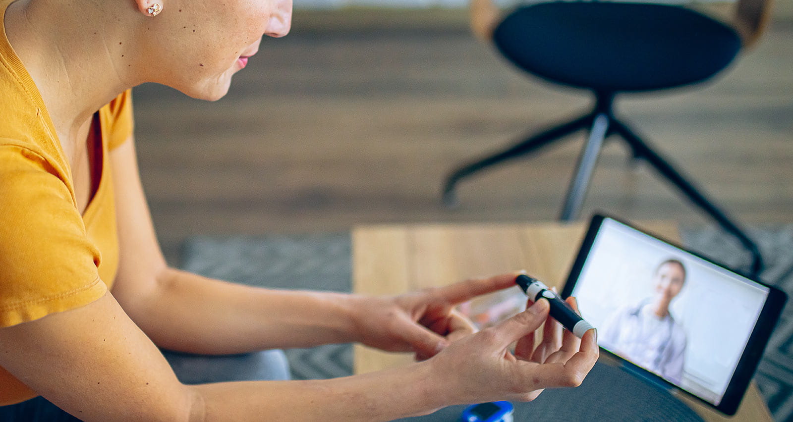 A young woman tests her blood sugar levels while on a video call with her doctor