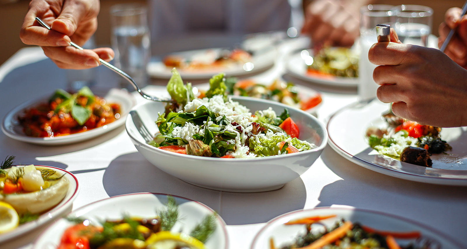 A couple eating lunch with fresh salad and appetizers