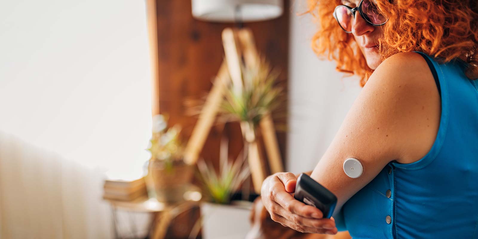 Woman checking her blood sugar level via continuous glucose monitor reader