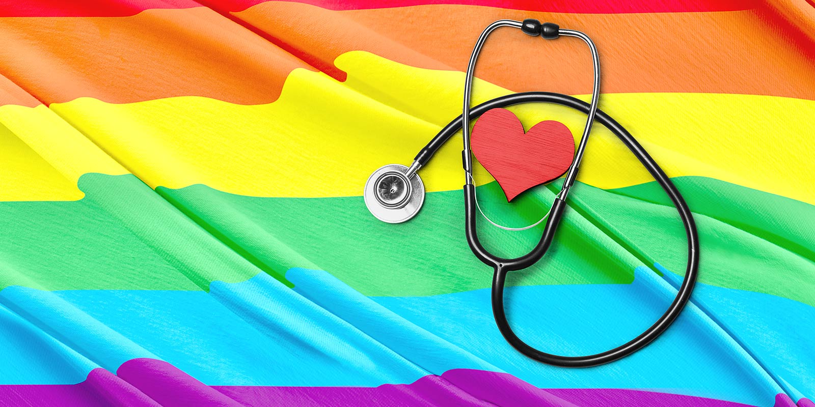 Stethoscope and heart shape atop rainbow flag