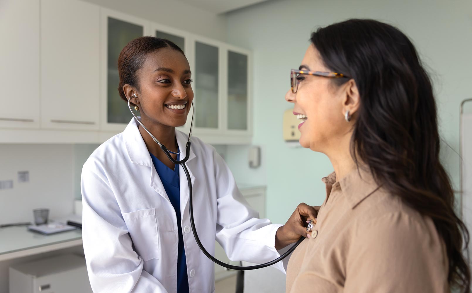 A young female doctor checking the heartbeat rate of a senior Caucasian woman in a hospital examination room