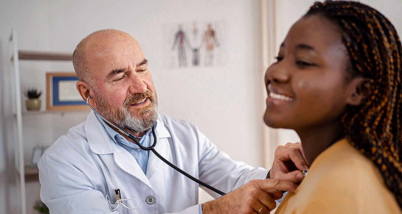 An older doctor examines a female patient with a stethoscope