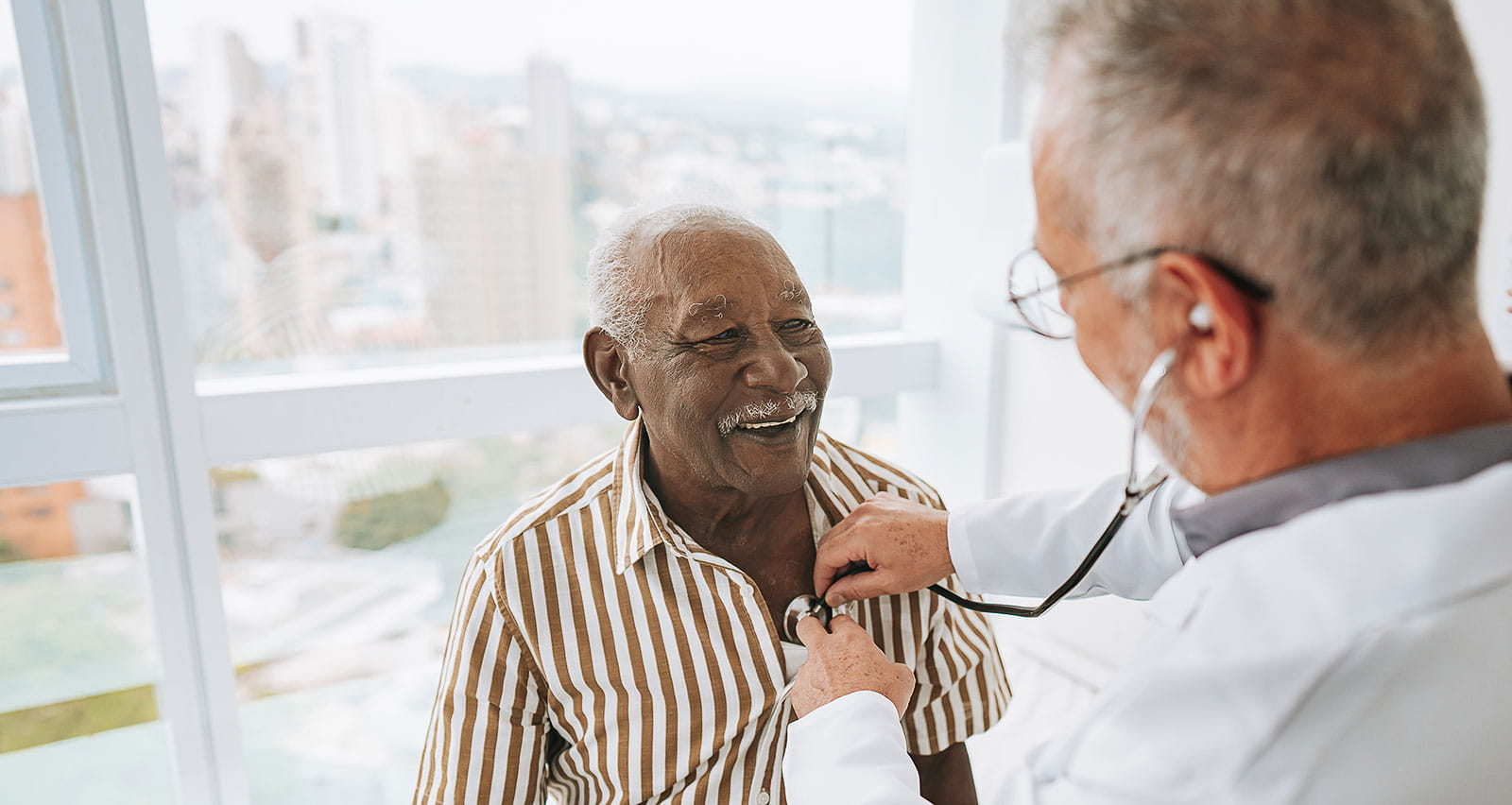 A doctor listening to an older patient's heartbeat