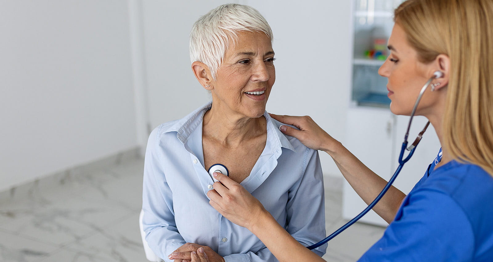 Young female doctor listens to a senior heart patient with a stethoscope