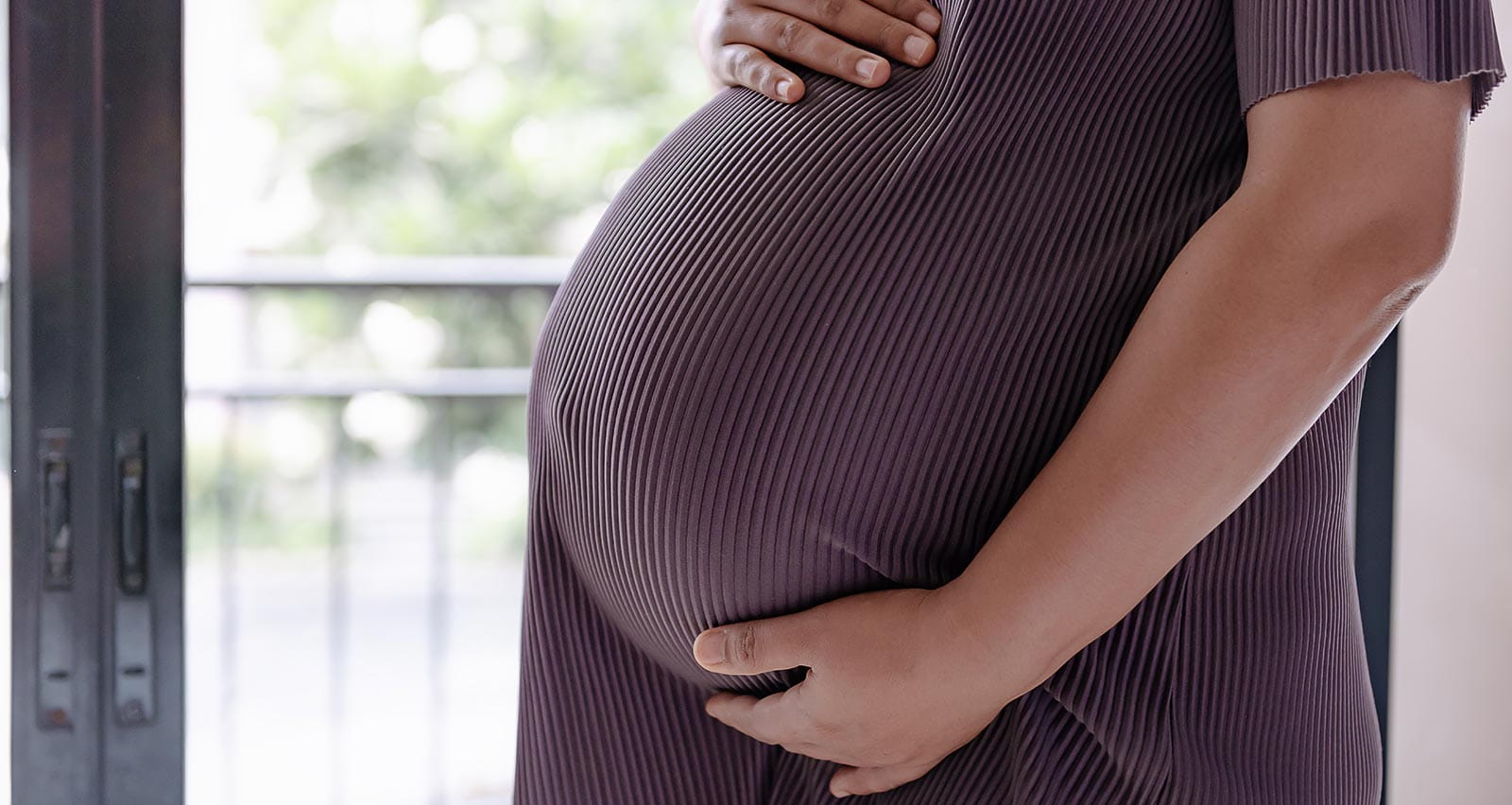 Close-up of the midsection of a pregnant woman holding her belly
