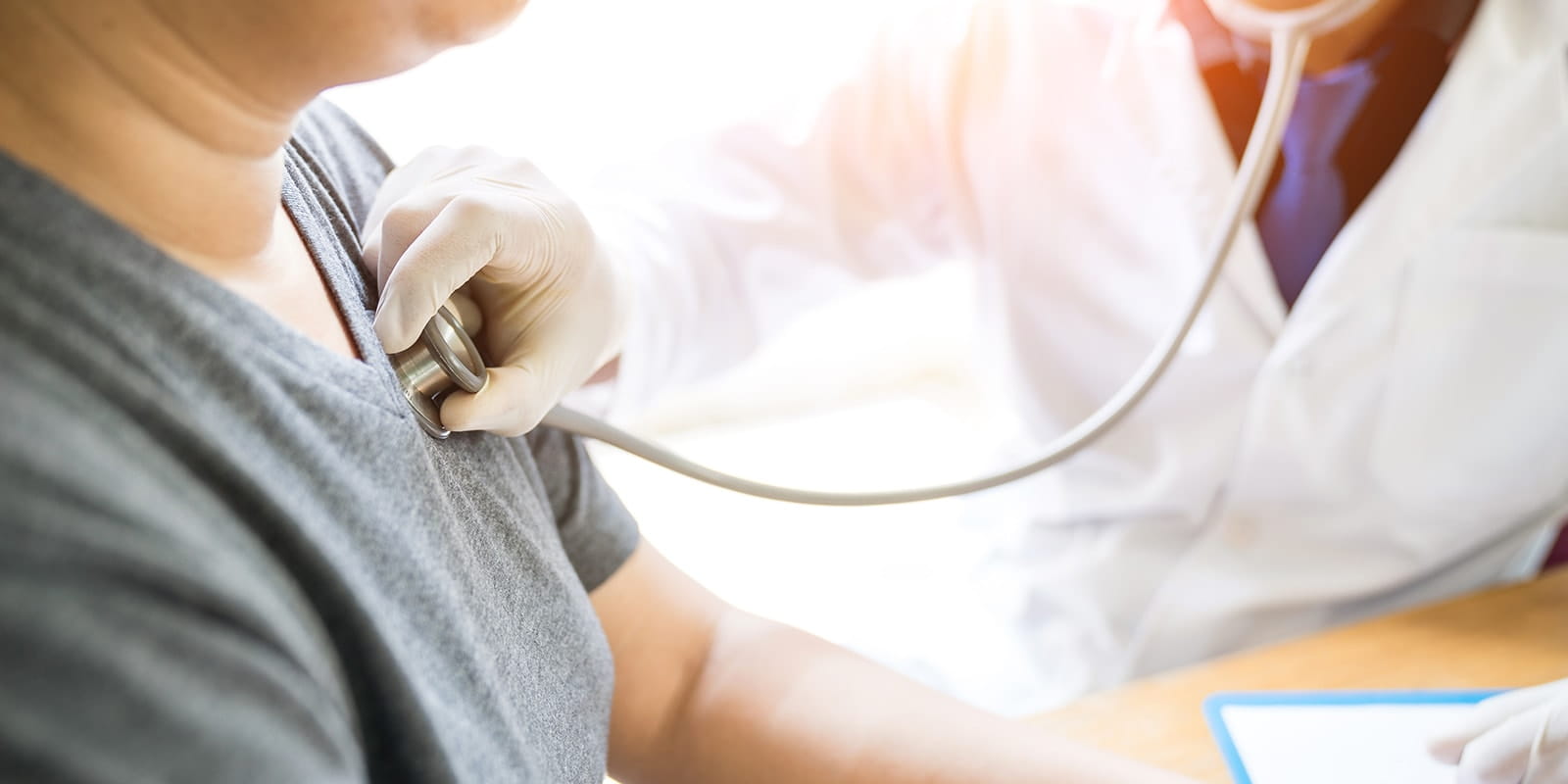 Doctor listening to woman's heartbeat.