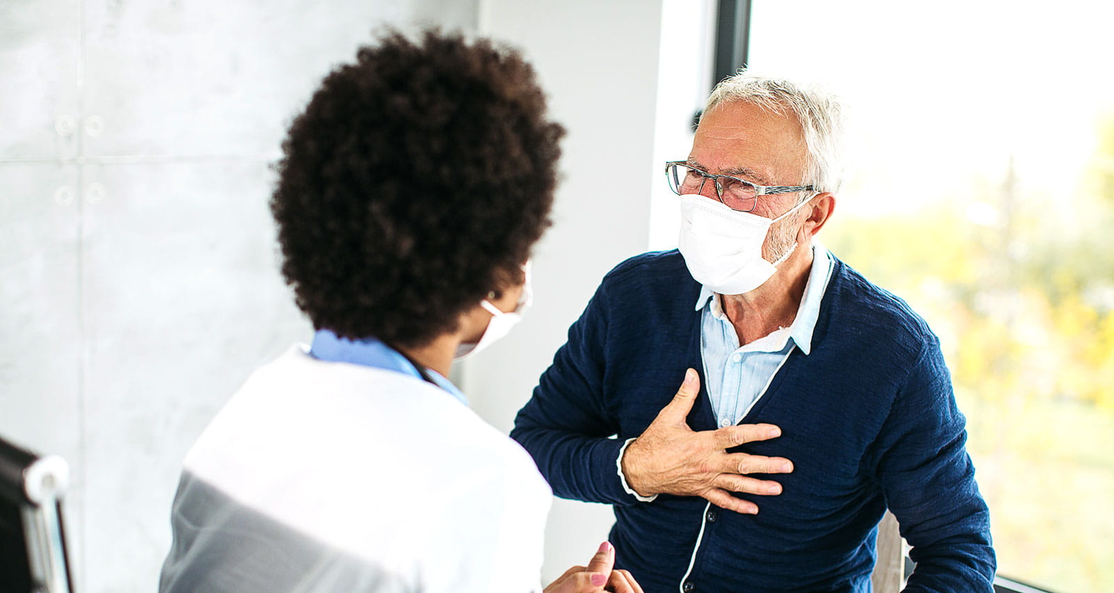 Female doctor examining senior male patient with heart issues