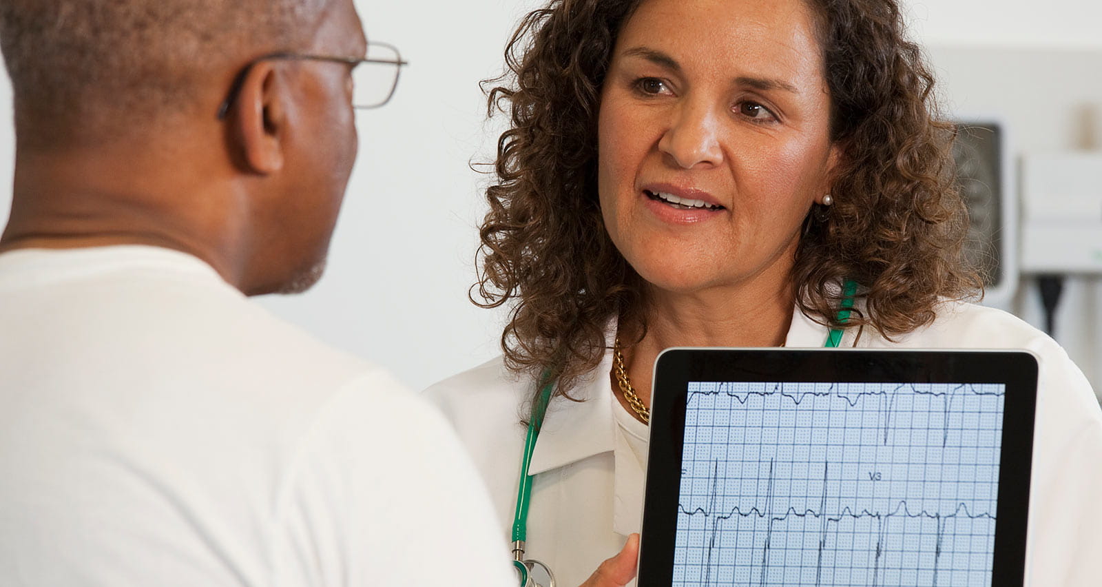 Doctor showing heart patient test results on digital tablet