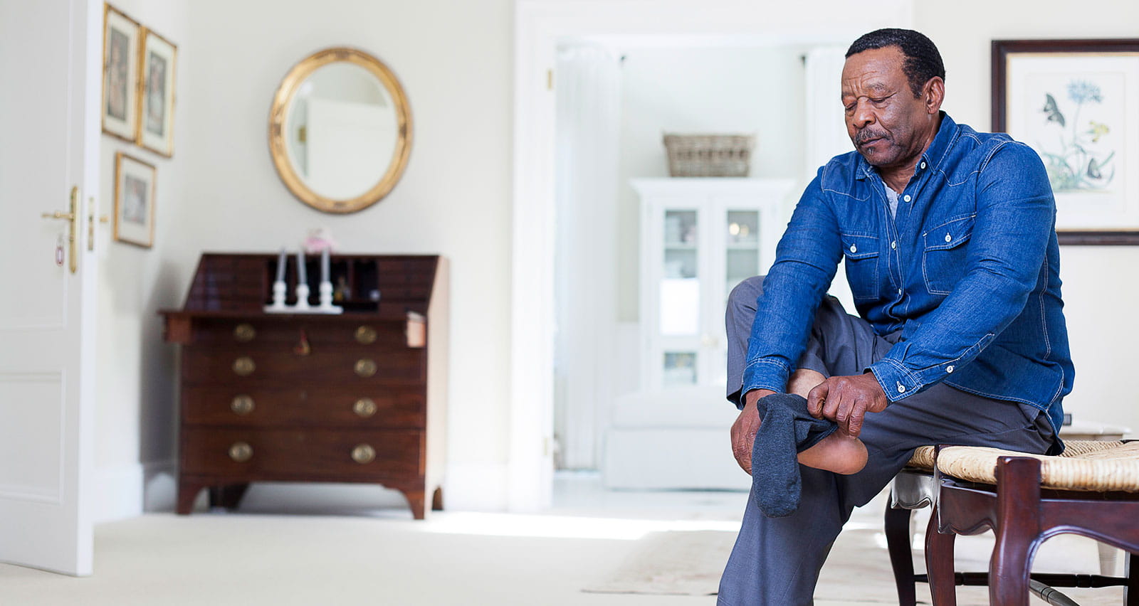 A senior man is putting on socks