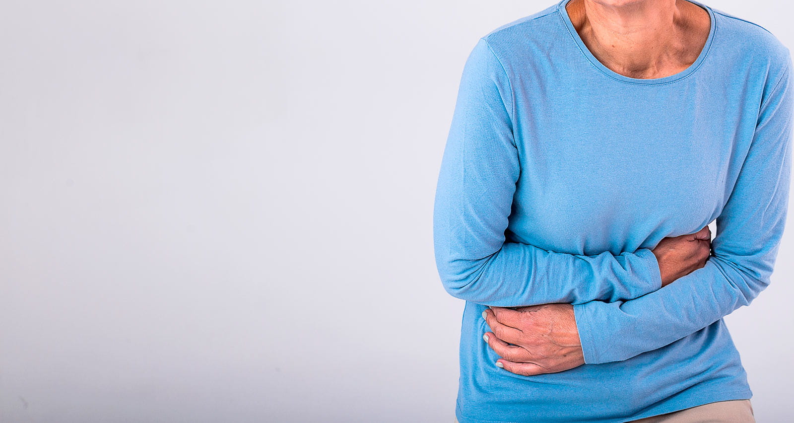 A mature woman holding her midsection in discomfort