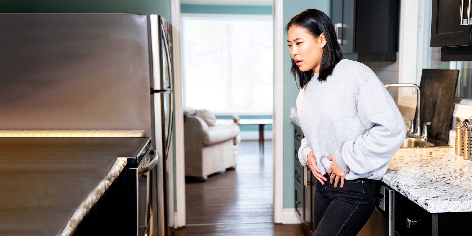 A young woman experiencing pelvic discomfort, she is grimacing in pain