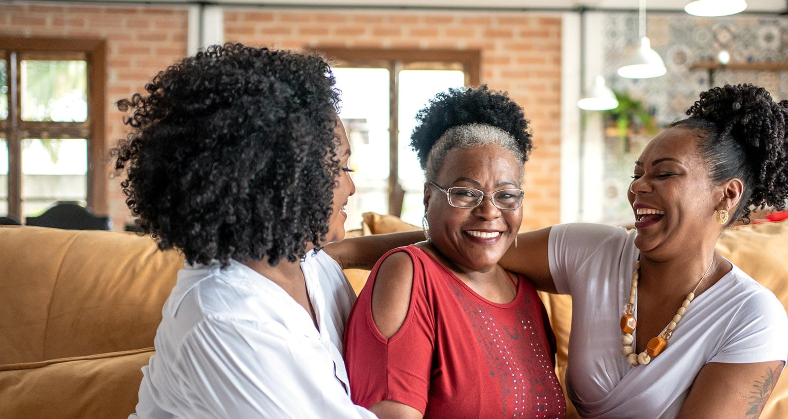 A smiling mother sits on a couch with her two daughters