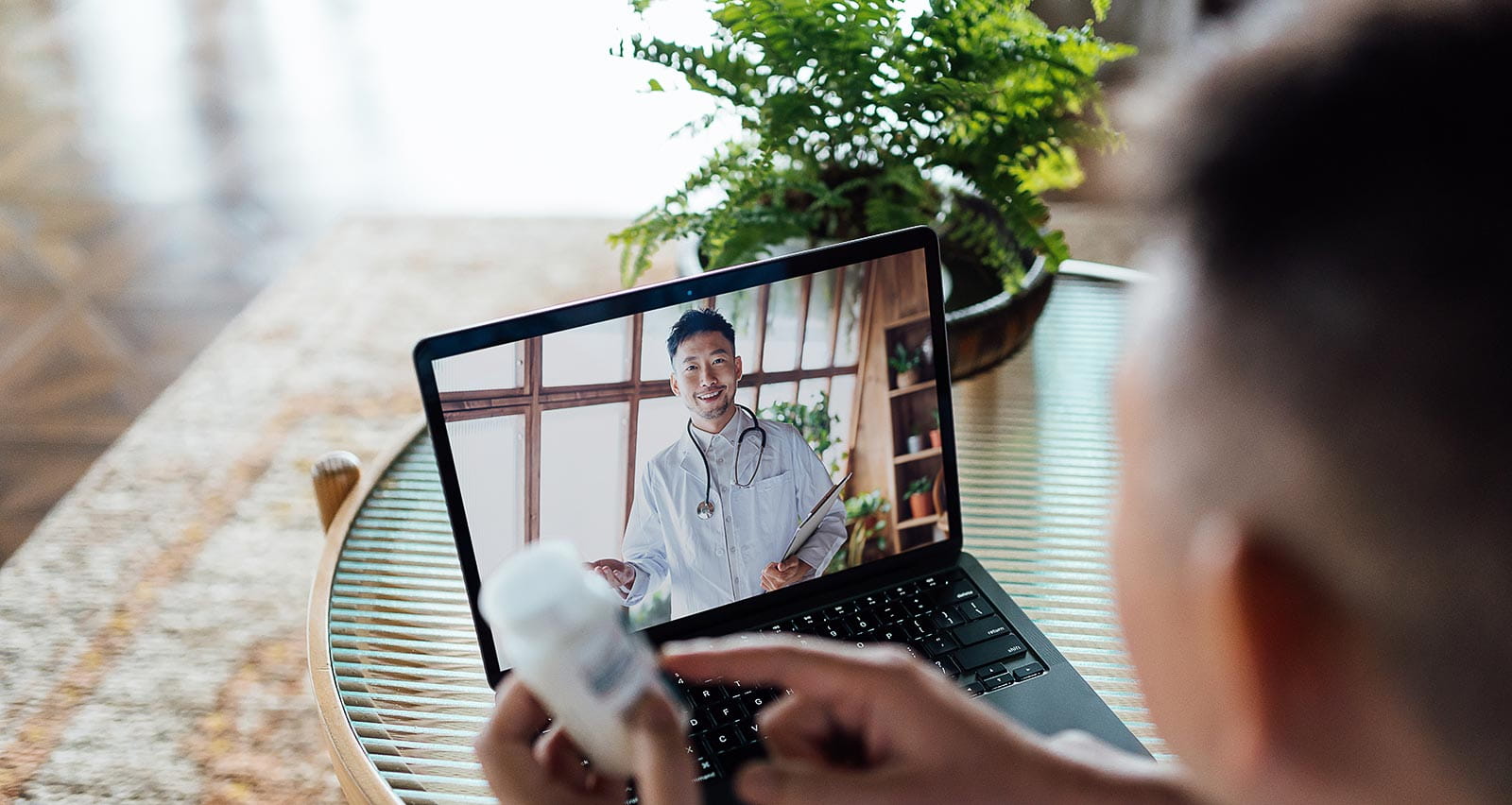 A senior man having a virtual appointment with doctor online, consulting about his prescription on a laptop at home