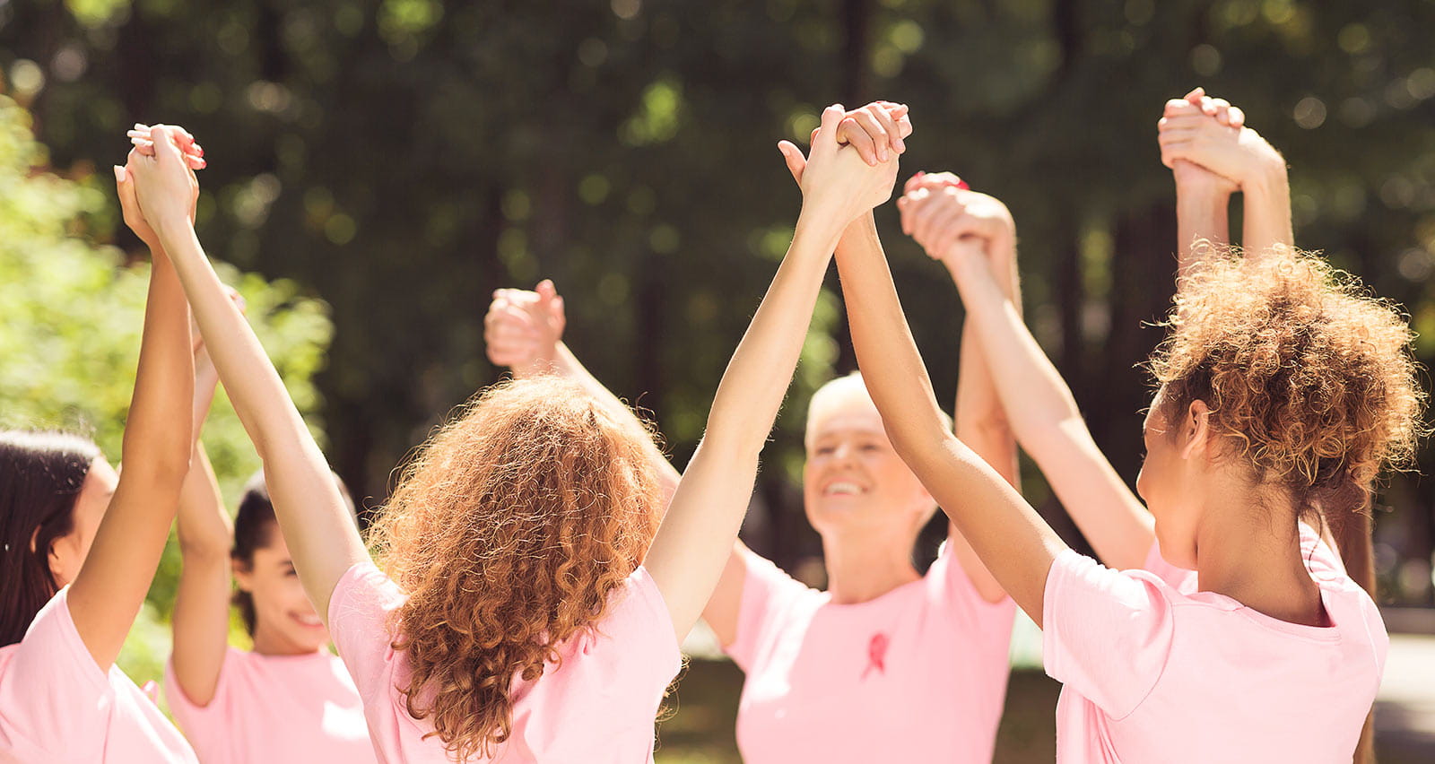 Female Volunteers participate in an Oncology Awareness Campaign event by holding their raised hands