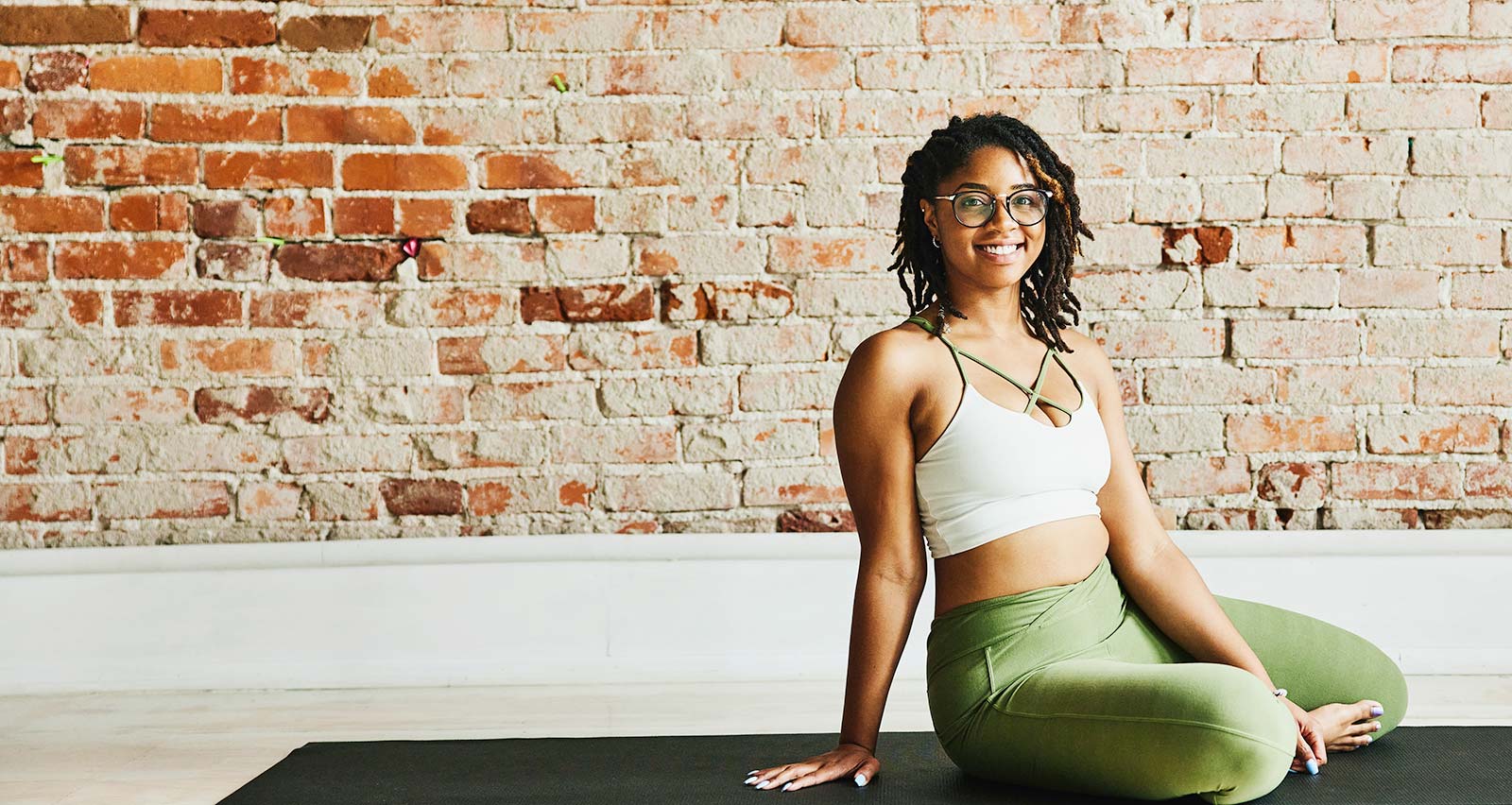 A smiling woman relaxing in a yoga studio after class